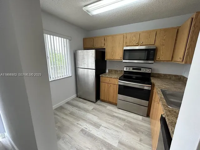 a kitchen with stainless steel appliances a refrigerator stove microwave and sink