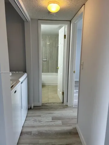 a view of a hallway with wooden floor and cabinet