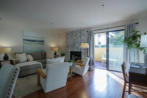 a living room with furniture a fireplace a potted plant and a large window