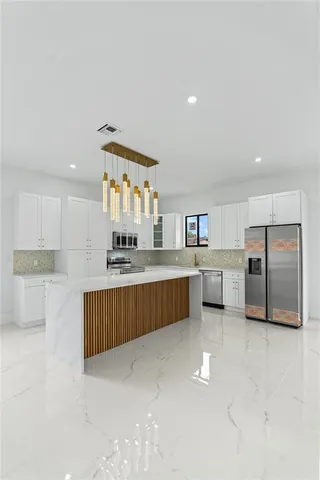a kitchen with stainless steel appliances a sink a stove a microwave a center island and cabinets