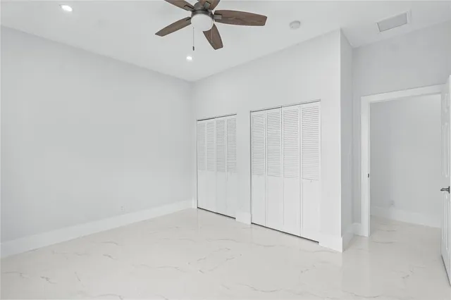 an empty room with a ceiling fan and carpet