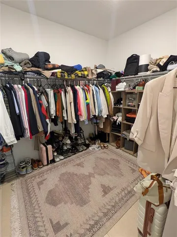 a view of walk in closet with clothes and shoes