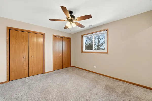 an empty room with closet and a chandelier fan