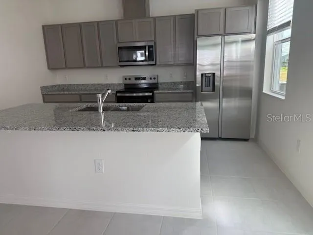 a kitchen with stainless steel appliances granite countertop a refrigerator a stove a sink and a granite counter tops