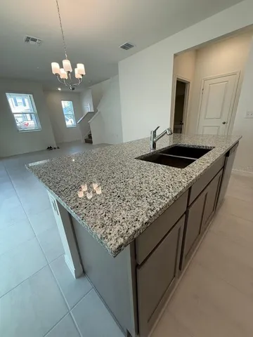 a kitchen with kitchen island granite countertop a sink and a stove