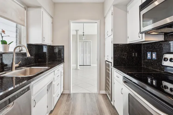 a kitchen with granite countertop a sink stove and cabinets