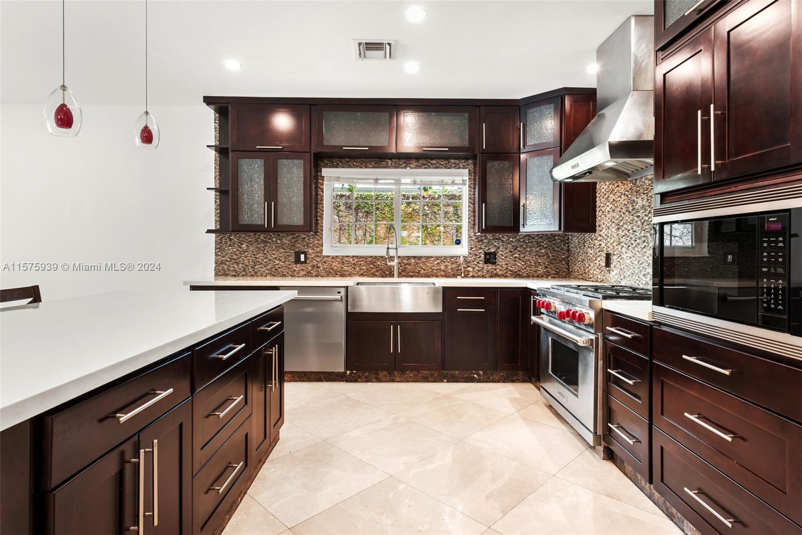 2811 Southwest 22nd Avenue Miami, FL 33133 - Photo 17 of 39 a kitchen with stainless steel appliances granite countertop a sink a stove top oven a chimney a counter space and a window