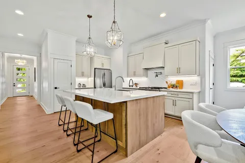 a kitchen with stainless steel appliances kitchen island granite countertop a table chairs sink and cabinets