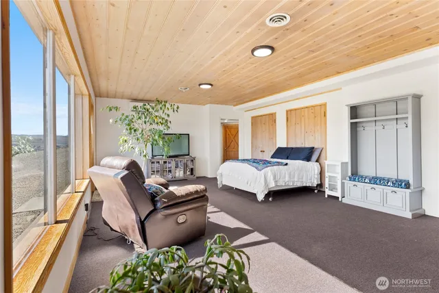 a bedroom with a bed a large window with table and chairs