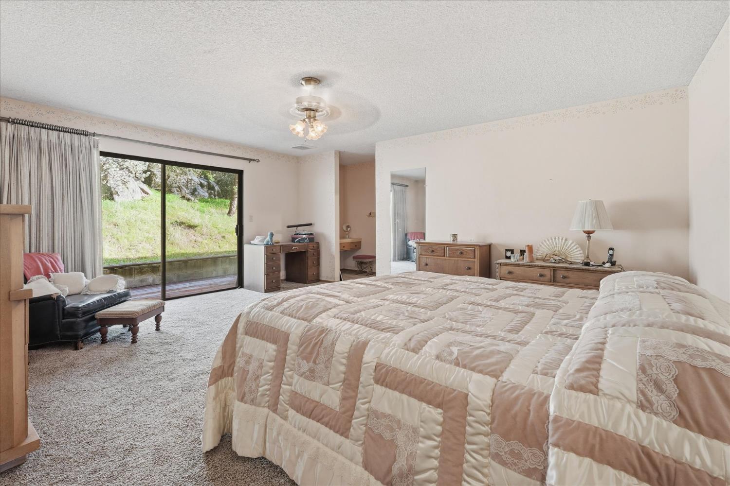 51590 Coyote Ridge Road Oakhurst, CA 93644 - Photo 29 of 49 a spacious bedroom with a bed and a chandelier