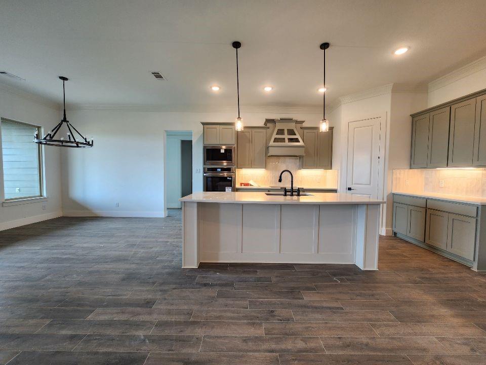 2408 Quartz Street Krum, TX 76249 - Photo 7 of 16 a kitchen with kitchen island a sink stainless steel appliances and cabinets
