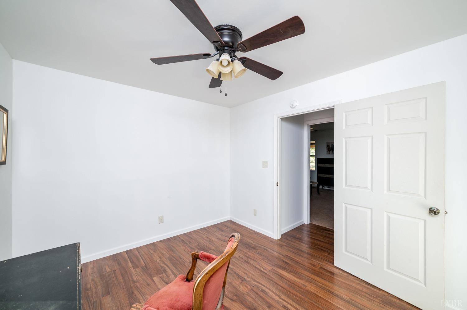 538 Spring Grove Road Spout Spring, VA 24593 - Photo 20 of 44 an empty room with wooden floor ceiling fan and windows