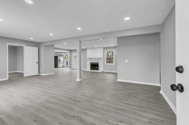 an empty room with wooden floor fireplace and windows