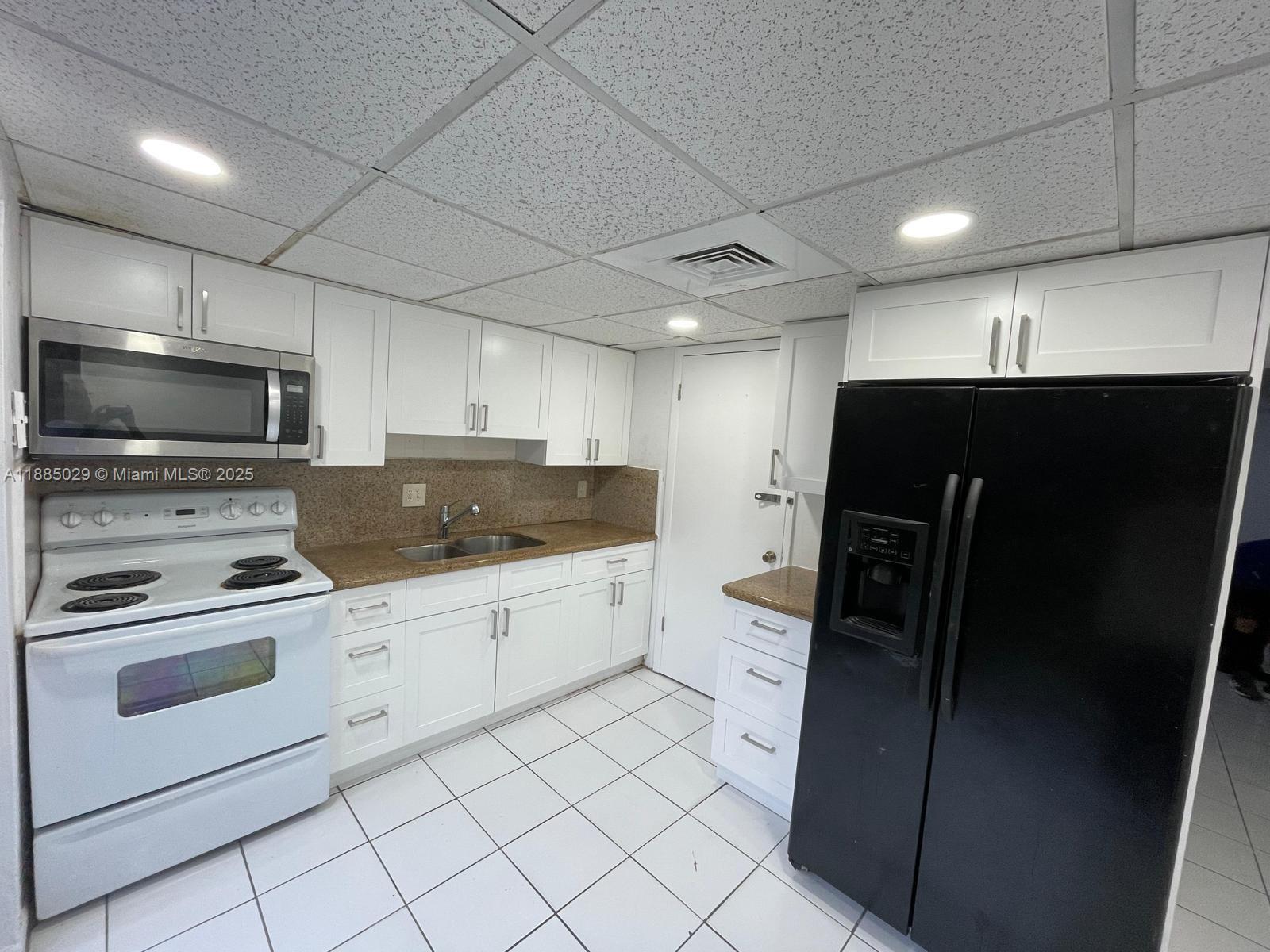a kitchen with granite countertop a refrigerator and a stove top oven