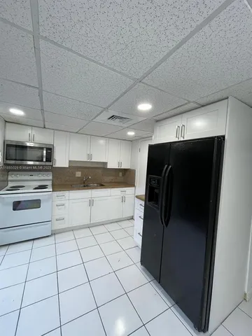 a kitchen with granite countertop a refrigerator and a stove top oven