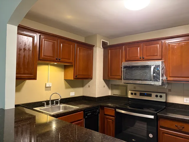 a kitchen with granite countertop a sink stainless steel appliances and cabinets