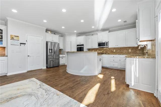a kitchen with stainless steel appliances kitchen island granite countertop a refrigerator and a stove top oven