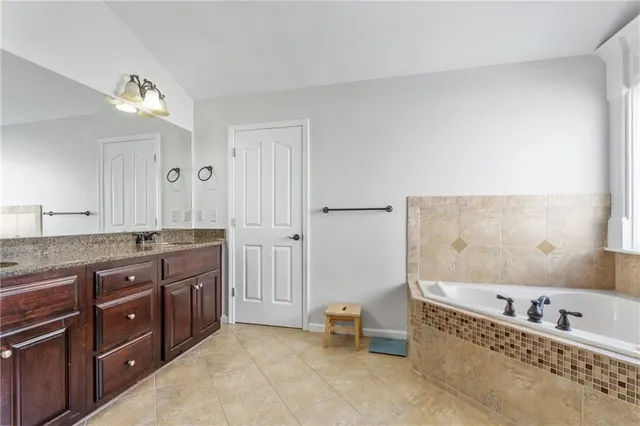 a bathroom with a tub a double vanity sink and a mirror