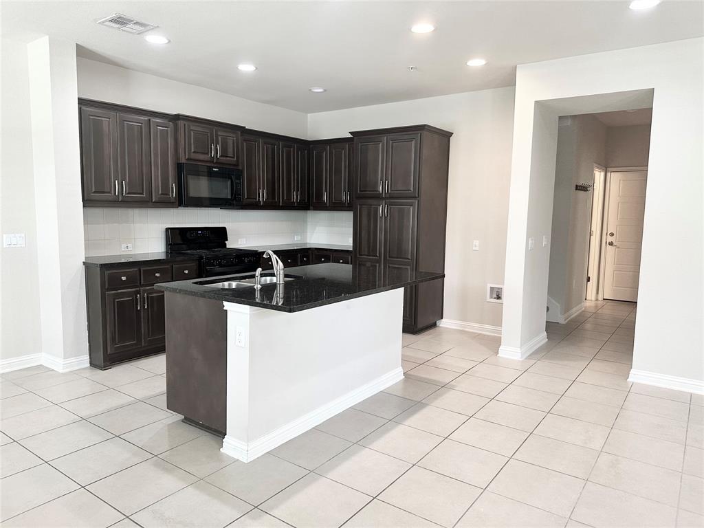 6814 East Riverside Drive, Unit 26 Austin, TX 78741 - Photo 4 of 21 A well-appointed kitchen showcasing an island, dark cabinetry, and tile flooring.