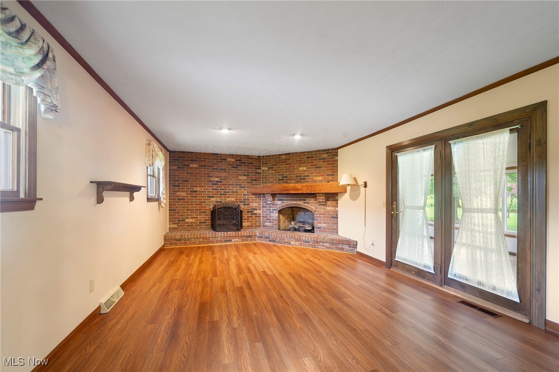 744 Johnson Plank Road Warren, OH 44481 - Photo 10 of 39 Family room with ornamental molding, a brick fireplace, plenty of natural light, and wood finished floors