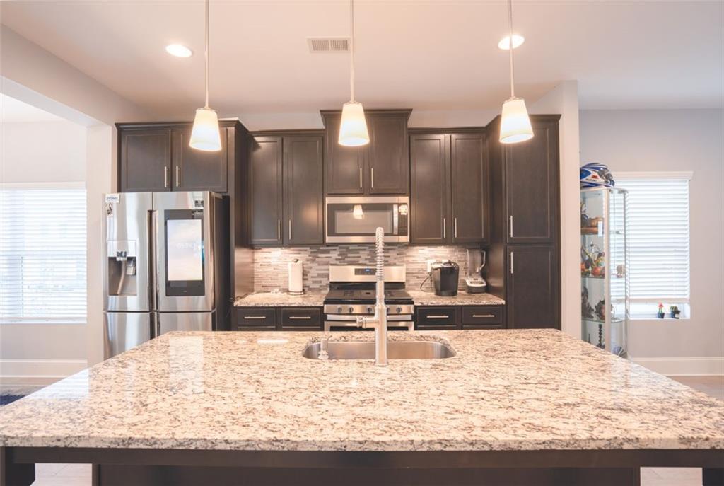 Undisclosed Address Atlanta, GA 30318 - Photo 17 of 19 a kitchen with kitchen island granite countertop wooden cabinets a refrigerator and a sink