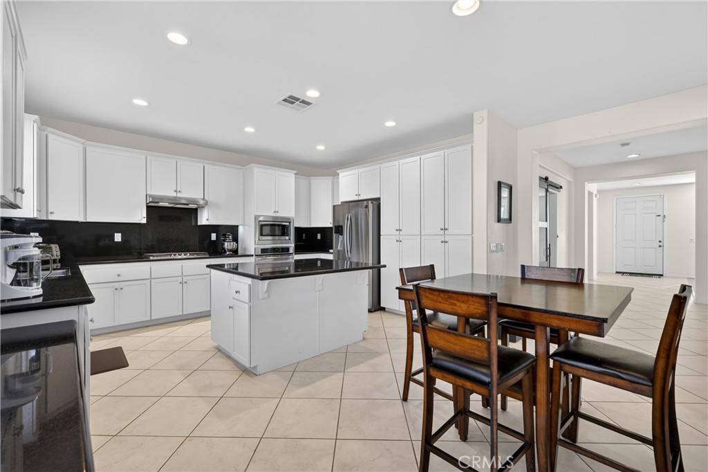 34581 Spindle Tree Street Winchester, CA 92596 - Photo 21 of 50 a kitchen with stainless steel appliances granite countertop a table chairs sink refrigerator and cabinets