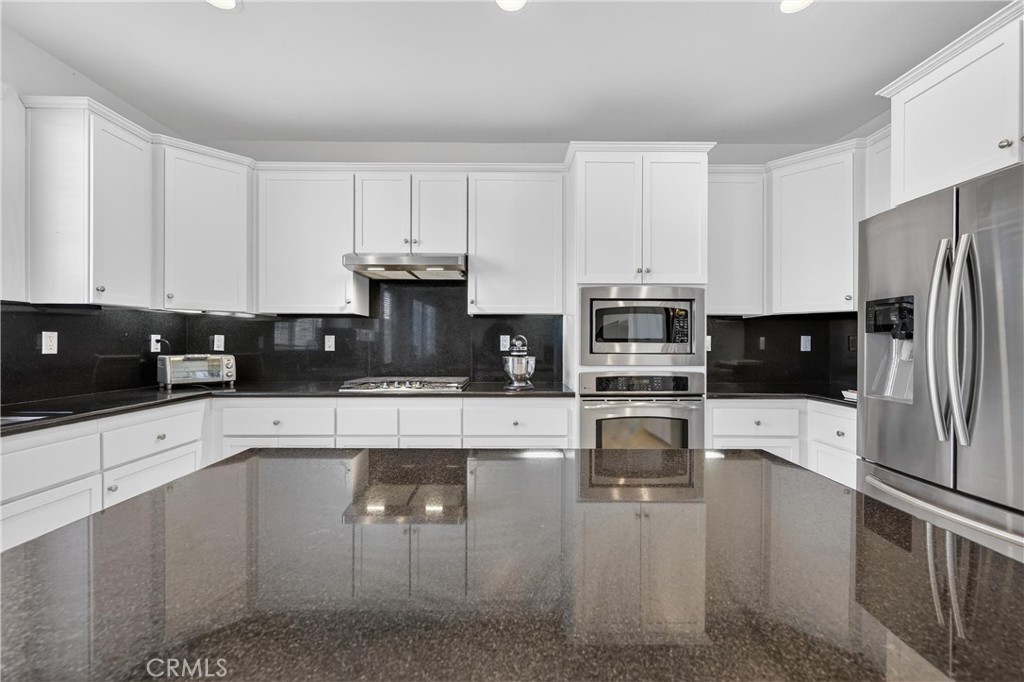 34581 Spindle Tree Street Winchester, CA 92596 - Photo 25 of 50 a kitchen with stainless steel appliances a stove a sink a refrigerator white cabinets and a granite counter top