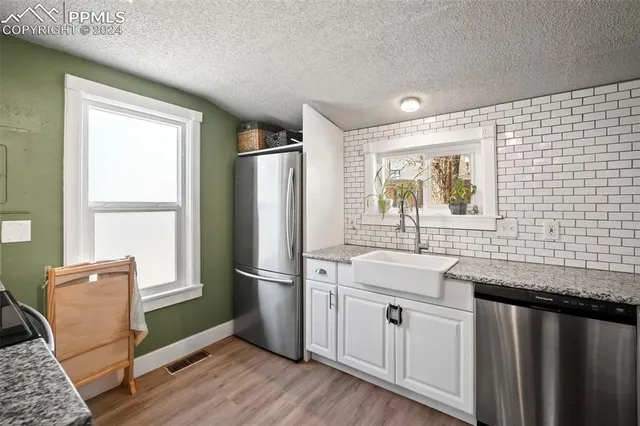 a kitchen with stainless steel appliances granite countertop a refrigerator sink and white cabinets