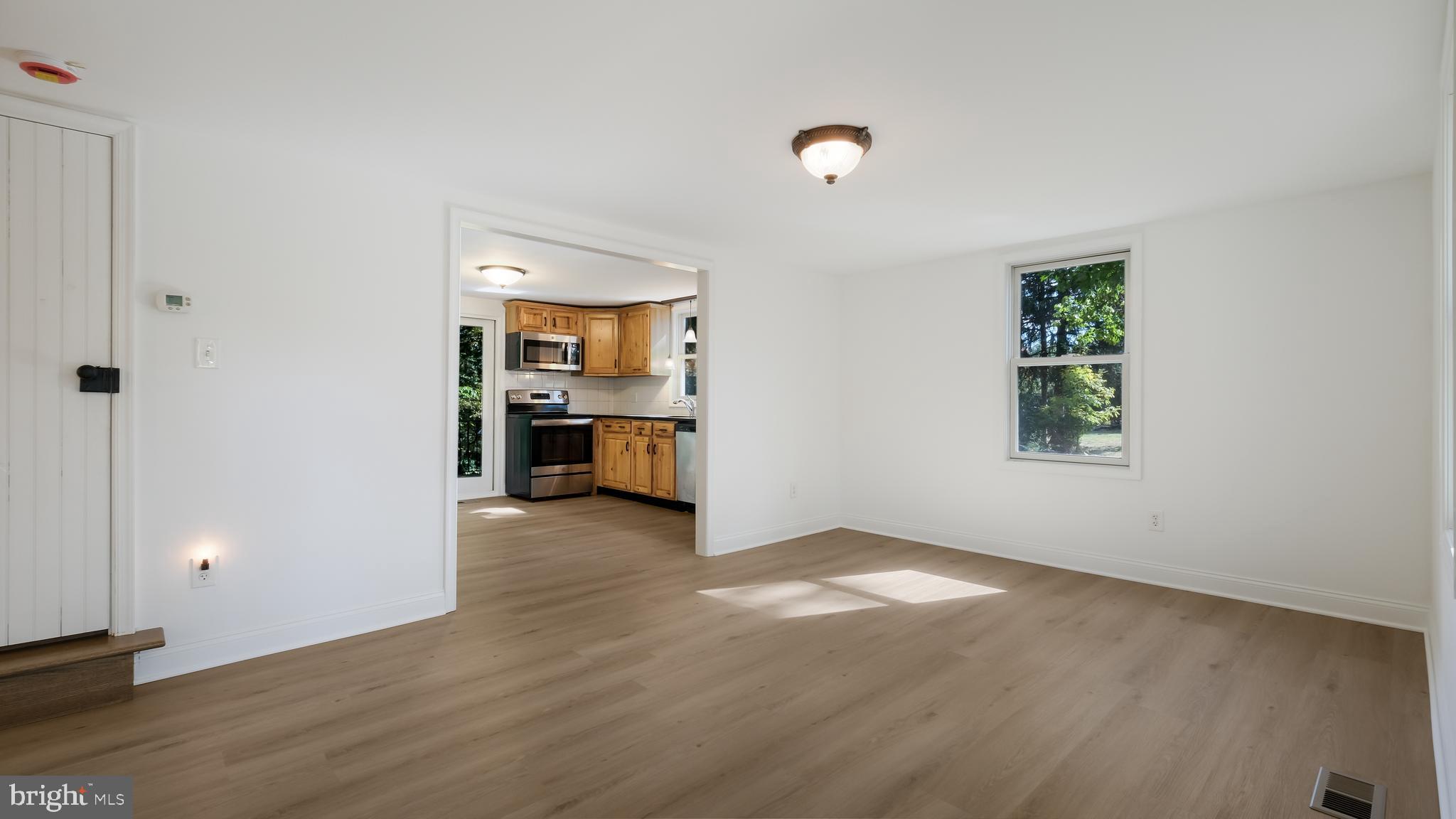 2443 Sugar Bottom Road Furlong, PA 18925 - Photo 7 of 39 an empty room with wooden floor kitchen view and a window