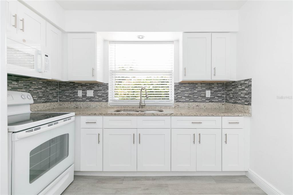 7531 Abonado Road, Unit 1 Tampa, FL 33615 - Photo 10 of 26 a kitchen with granite countertop white cabinets stainless steel appliances a sink and a window