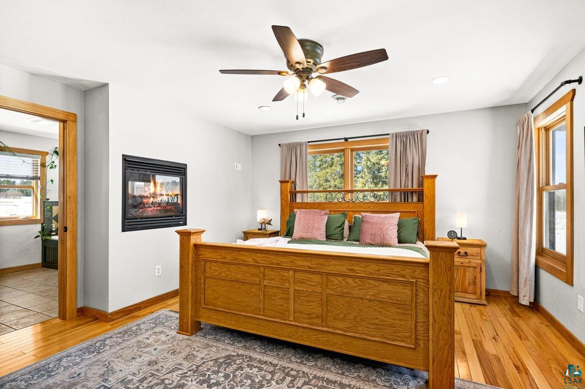 27 West Stark Road Esko, MN 55733 - Photo 21 of 47 Bedroom featuring light wood finished floors, ceiling fan, a multi sided fireplace, and recessed lighting
