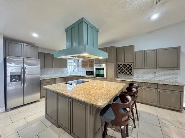 a kitchen with stainless steel appliances granite countertop a sink and a refrigerator