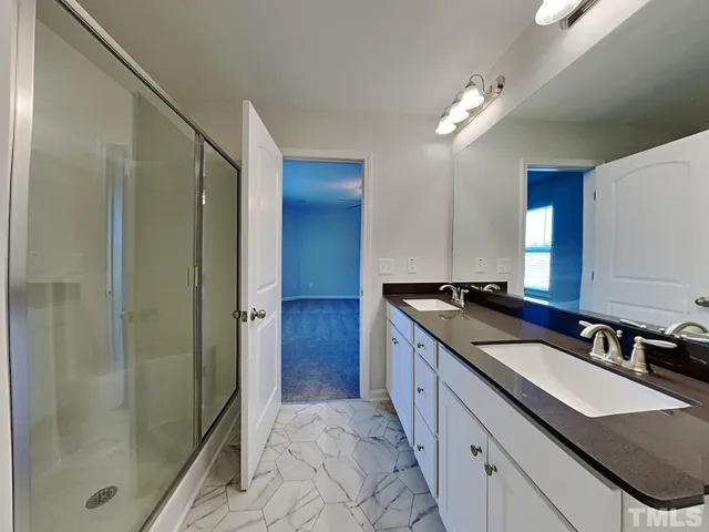 a bathroom with a granite countertop sink two mirror and shower