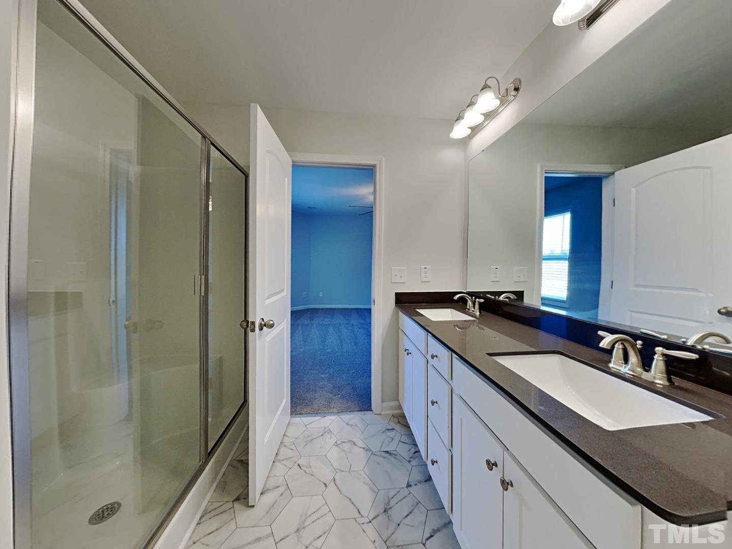 a bathroom with a granite countertop sink two mirror and shower