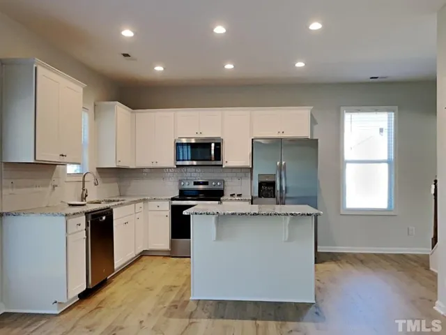 a kitchen with stainless steel appliances granite countertop a stove top oven a sink and a refrigerator