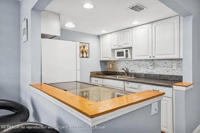 a kitchen with stainless steel appliances granite countertop a sink and a refrigerator