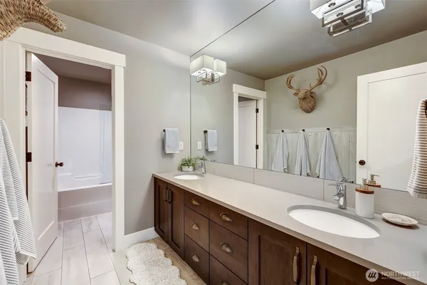 a bath room with a sink vanity granite tub shower and a mirror