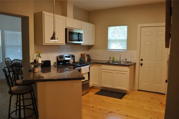 a kitchen with stainless steel appliances granite countertop a sink a stove a microwave a counter top space and cabinets