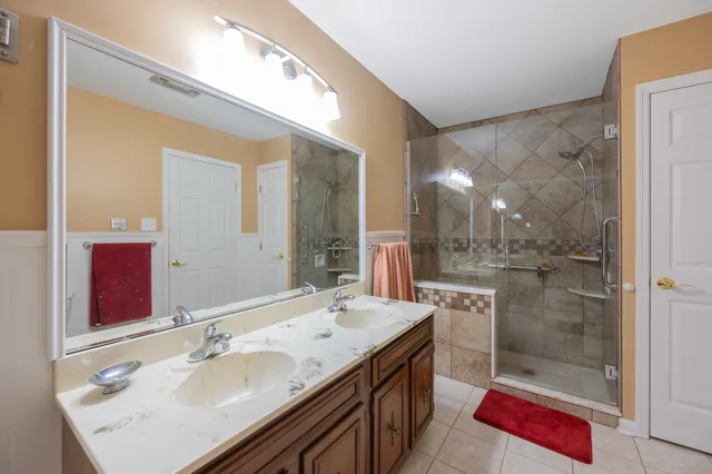 a bathroom with a granite countertop sink a mirror and shower