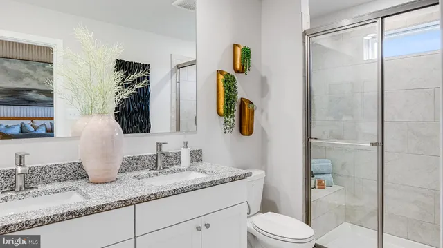 a bathroom with a granite countertop sink a toilet and shower