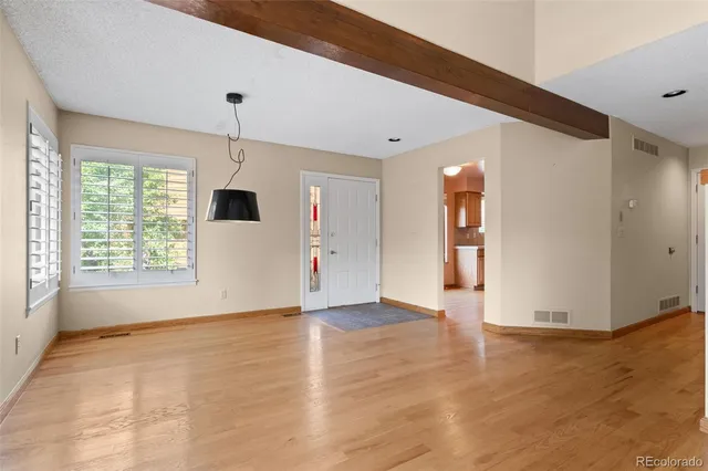 a view of an empty room with window and wooden floor