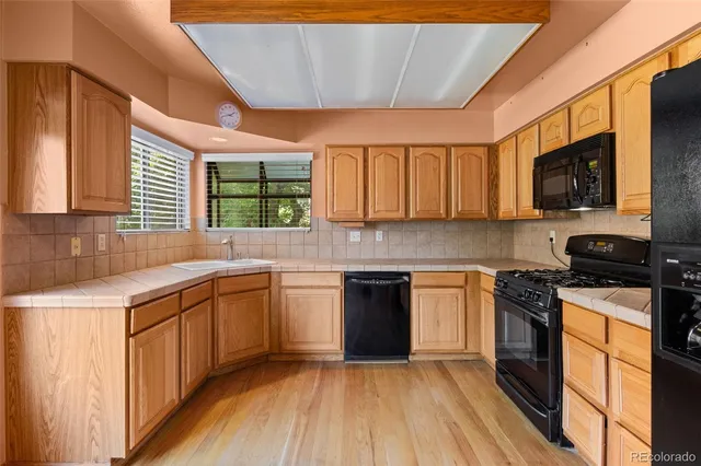 a kitchen with stainless steel appliances granite countertop wooden cabinets a stove top oven a sink and dishwasher with wooden floor