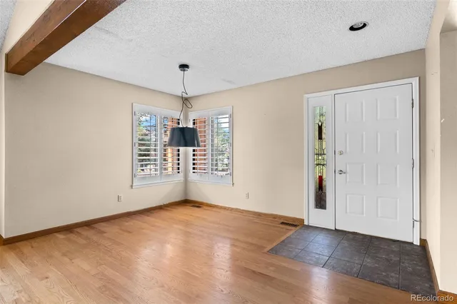 a view of an empty room with kitchen and window