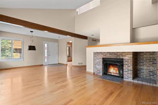 a view of an empty room with wooden floor fireplace and a window