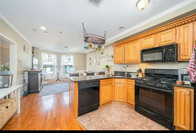 a kitchen with stainless steel appliances granite countertop a stove top oven a sink dishwasher a dining table and chairs with wooden floor