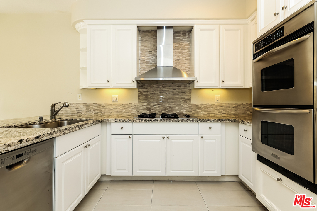 6 Alamitos Foothill Ranch, CA 92610 - Photo 4 of 27 a kitchen with granite countertop white cabinets stainless steel appliances and a sink