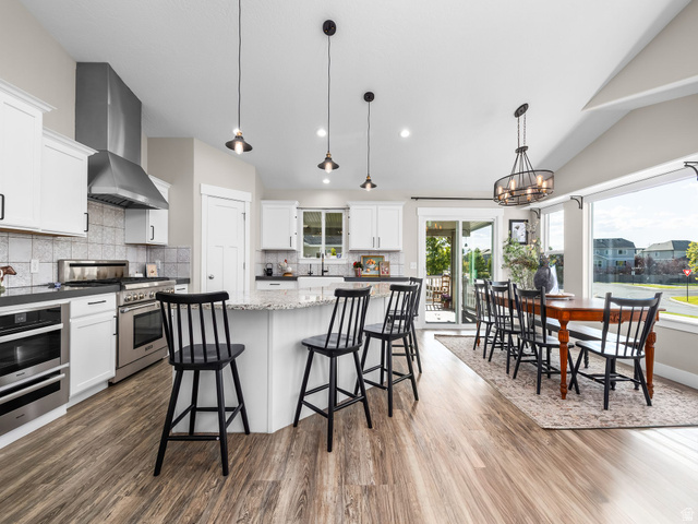7 Sterling Loop Vineyard, UT 84059 - Photo 11 of 43 Open-concept kitchen and dining area featuring wood-finish flooring, white cabinetry, and stainless steel appliances