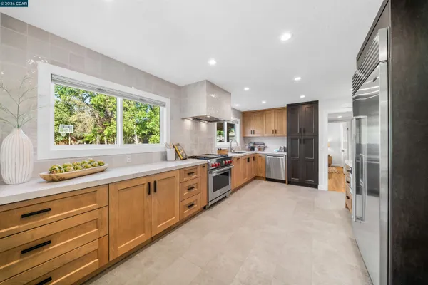 a large kitchen with stainless steel appliances kitchen island granite countertop a refrigerator and a sink