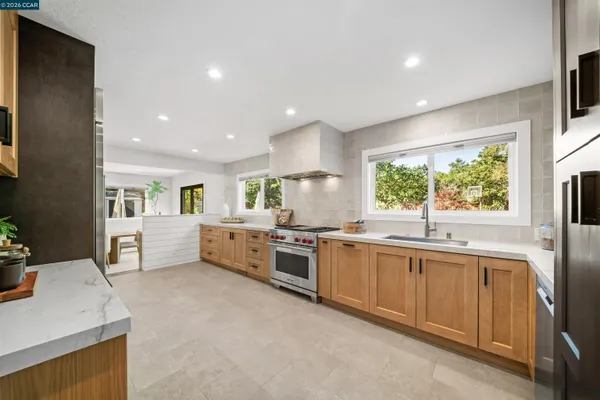 a large kitchen with stainless steel appliances granite countertop a sink and dishwasher a stove a dining table with wooden floor