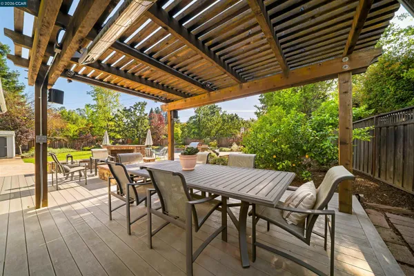 a view of a patio with table and chairs under an umbrella with a barbeque